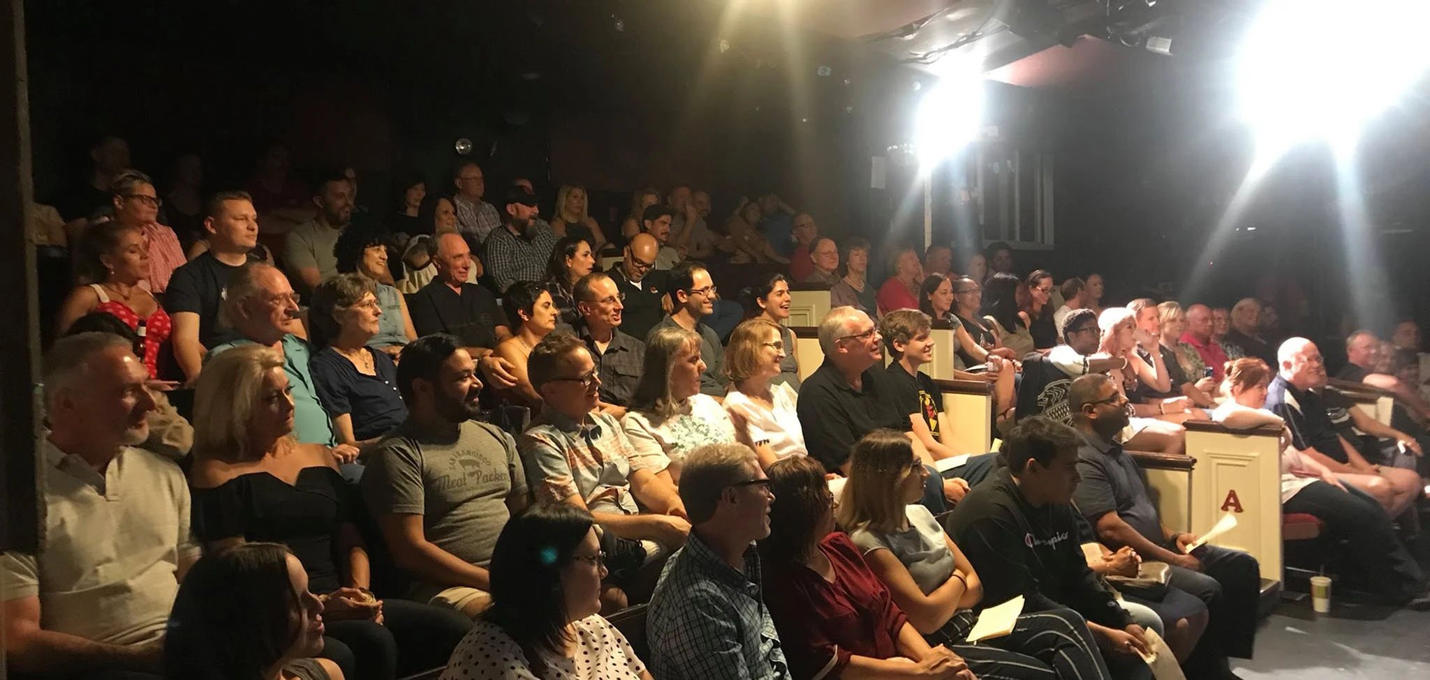 The audience attending the Plano Comedy Festival in theater seats.