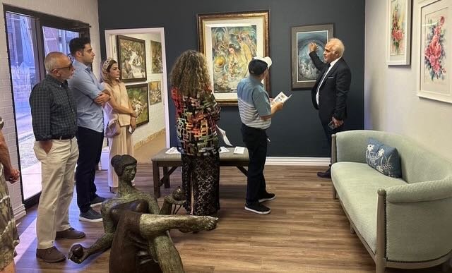 A man in a jacket and tie viewing artwork on a brick wall.